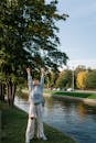 Person Standing on Green Grass Stretching Arms Up