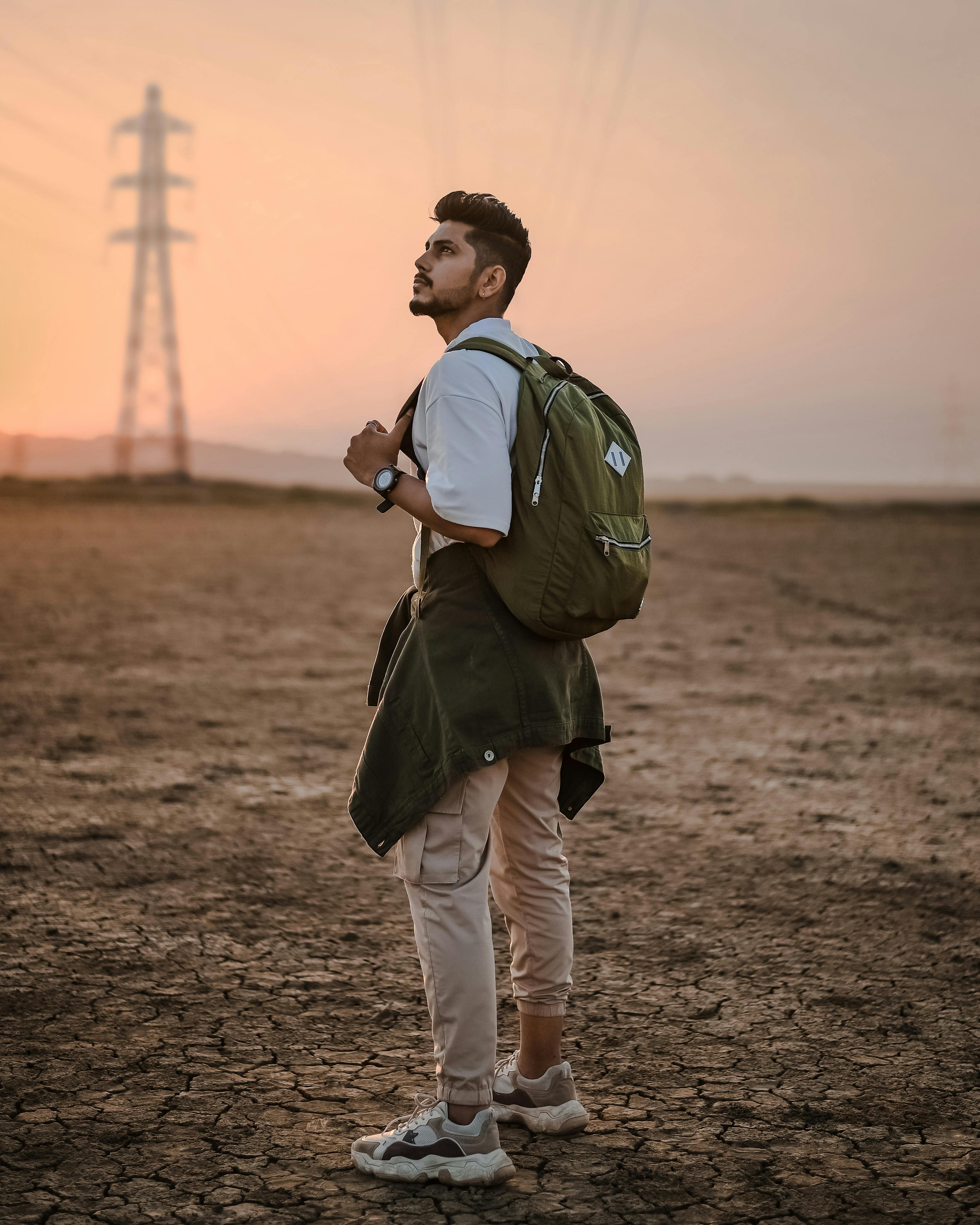 a man in white polo shirt carrying a green backpack