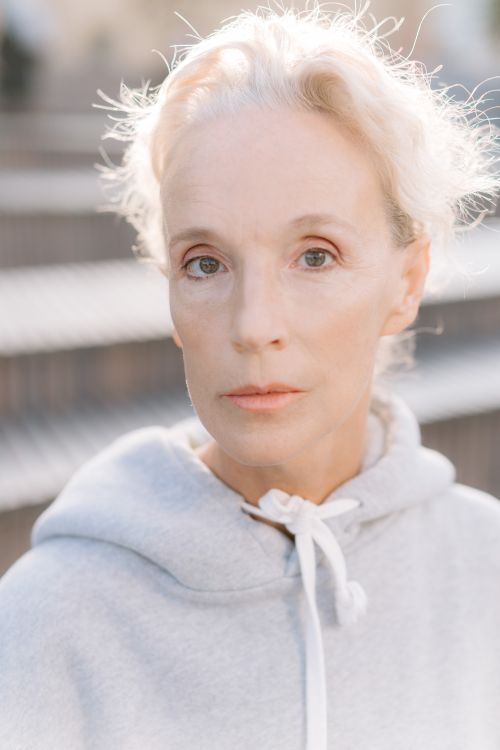 Free Close-up portrait of a senior woman in a gray hoodie, outdoors with soft lighting. Stock Photo