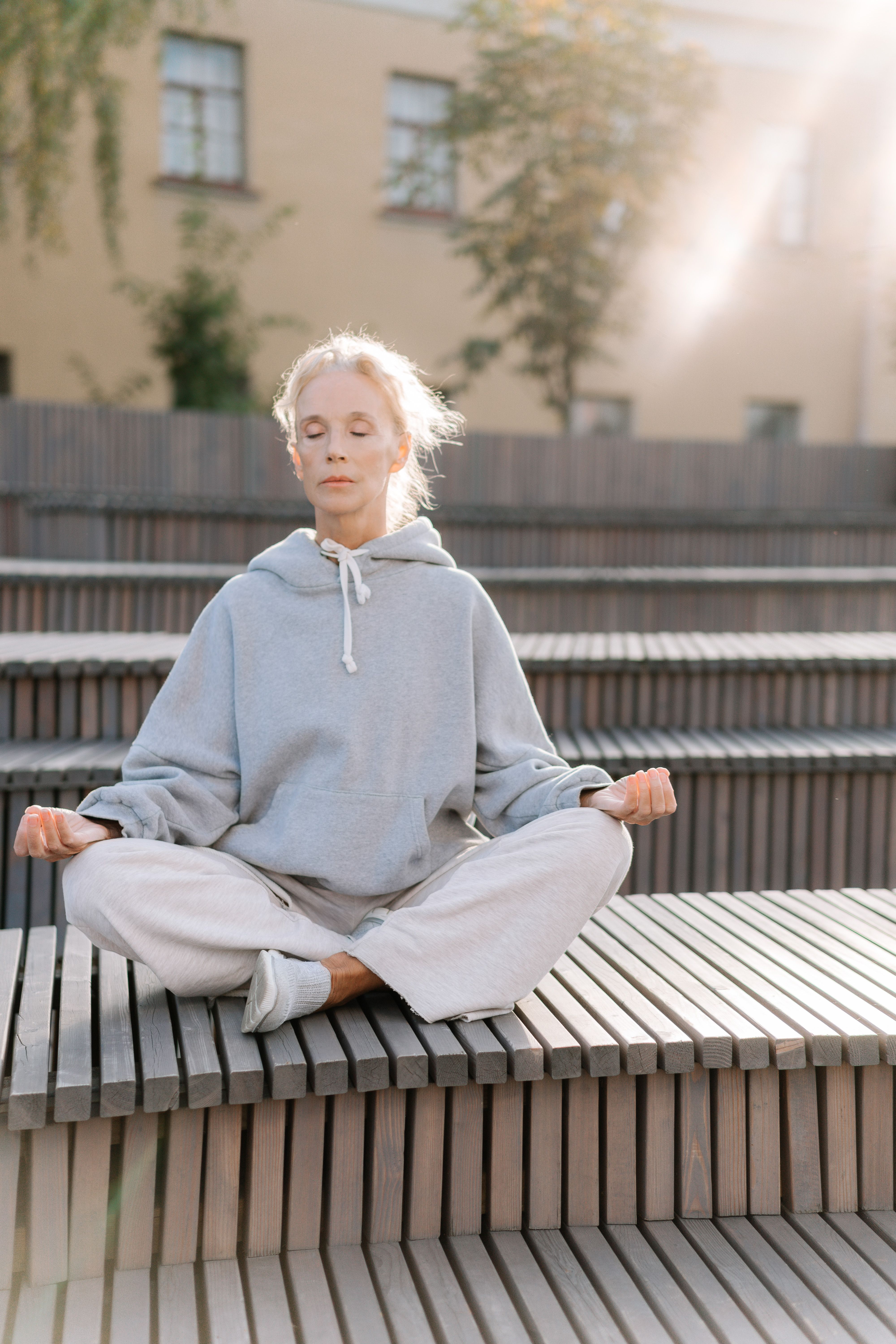 Serene elderly woman meditating outside in comfortable sportswear, eyes closed and relaxed.