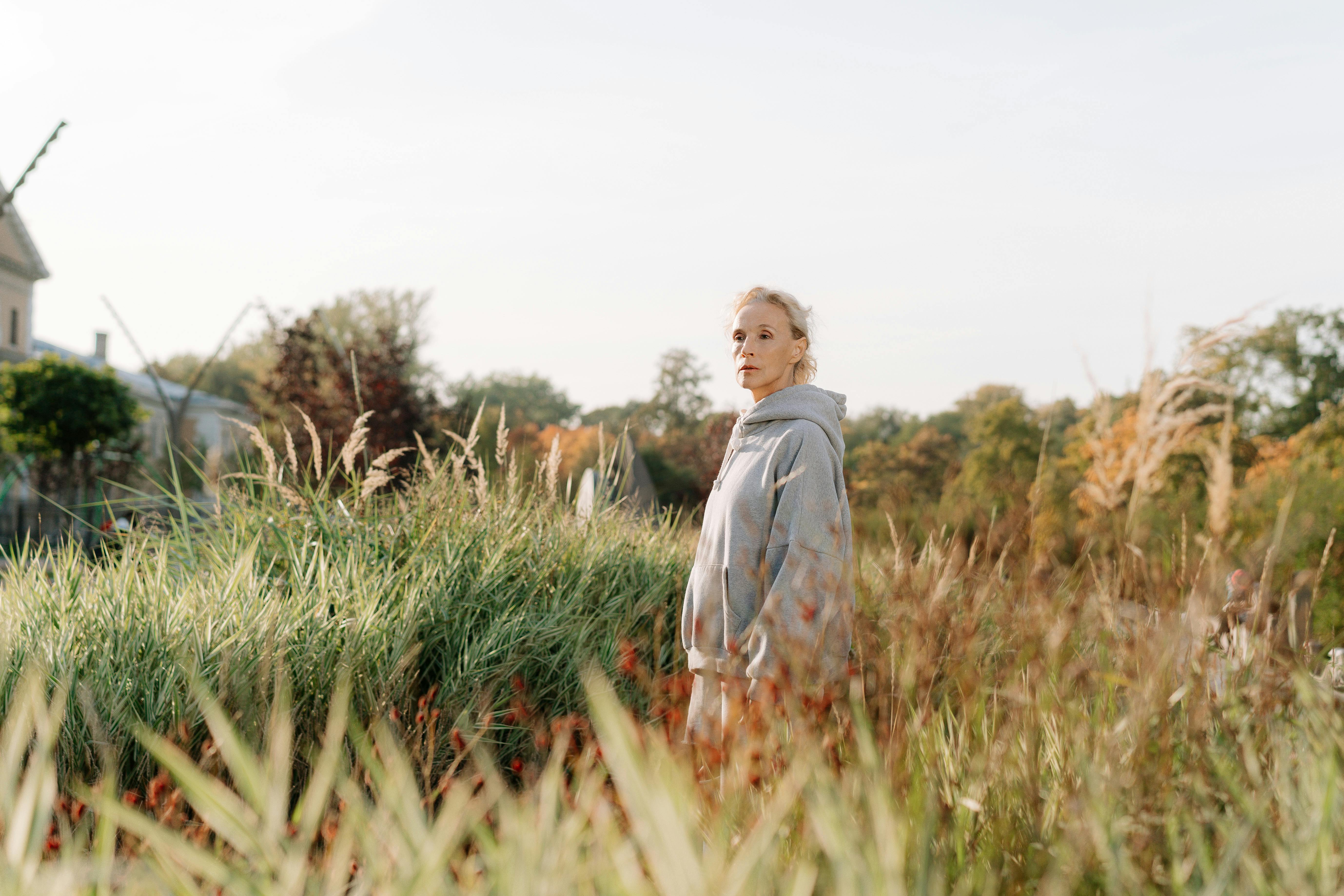 a woman in gray hoodie standing near the green grass
