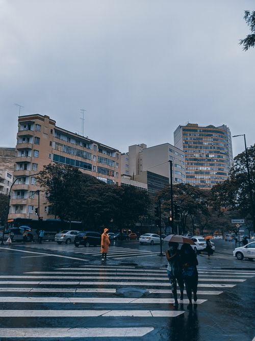 Free People crossing the street during rainy weather in Belo Horizonte's city center, surrounded by buildings. Stock Photo