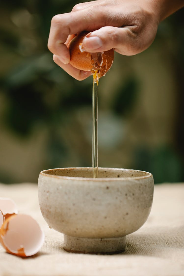 Woman Pouring White From Cracked Chicken Egg