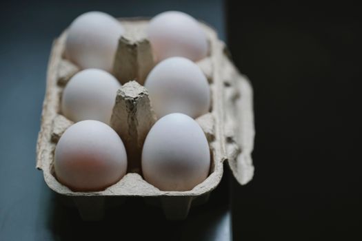 From above of white eggs in cardboard container placed on table for cooking