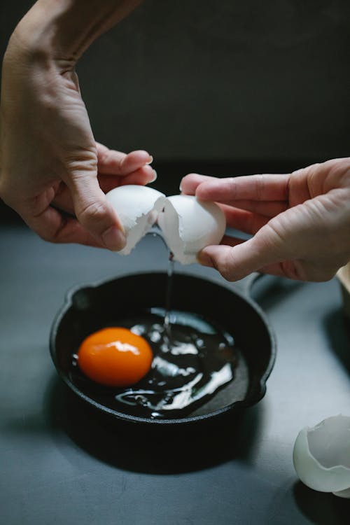 Woman breaking eggs into pan for breakfast