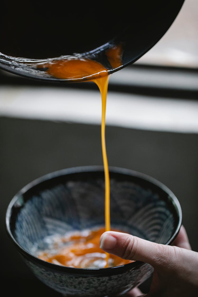 Anonymous Woman Pouring Egg Yolk Into Bowl In Kitchen