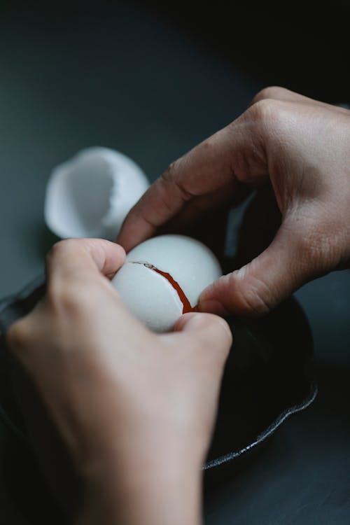 Unrecognizable person pouring egg into frying pan in kitchen