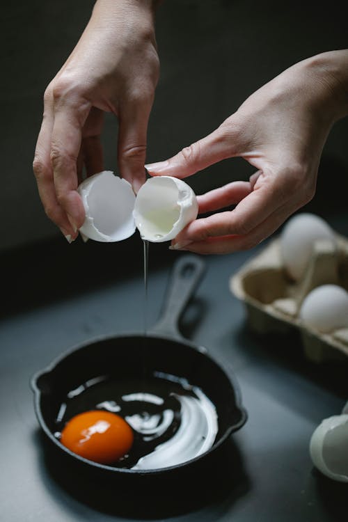 Free Crop female preparing fried eggs for breakfast at home Stock Photo