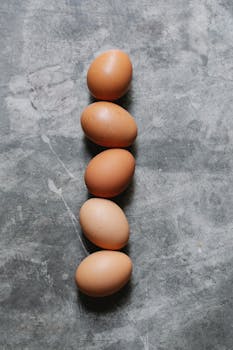Top view of fresh healthy raw brown eggs placed in row on gray surface in kitchen