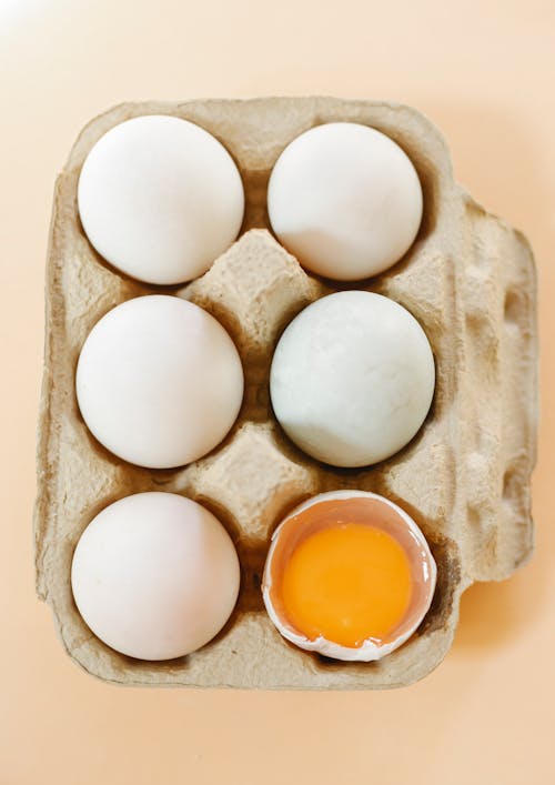 Box of healthy organic chicken eggs on beige surface