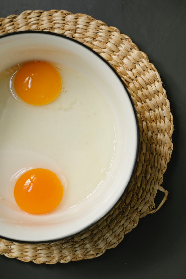 Egg Yolks And Whites In Mixing Bowl Placed On Table In Kitchen