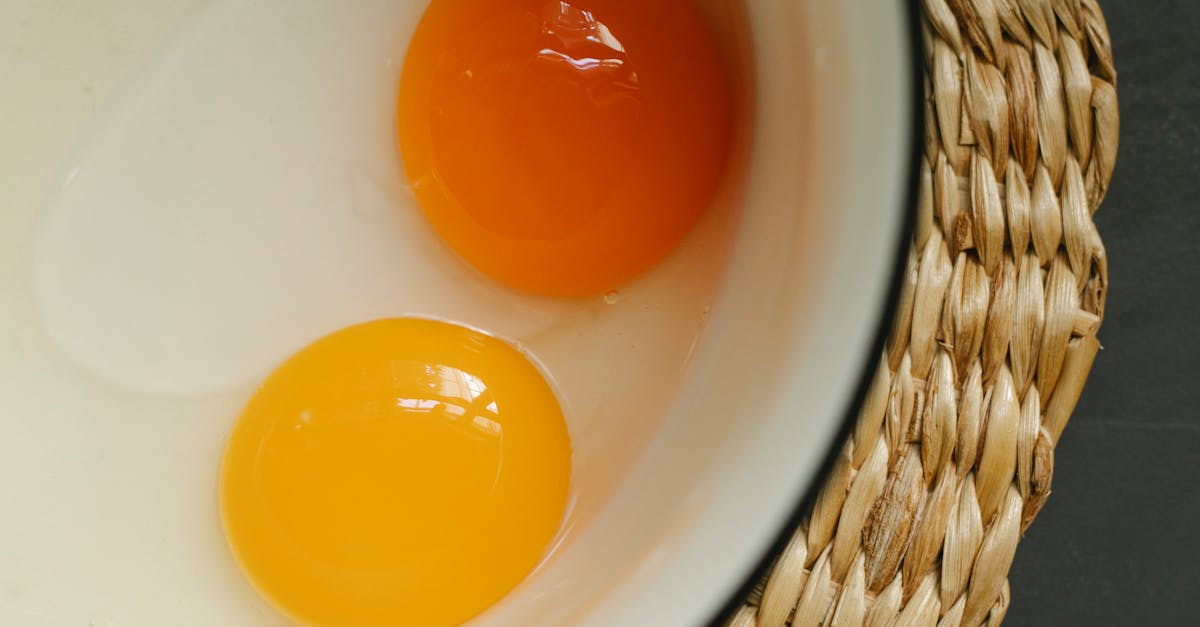 Raw eggs in enamel bowl placed on rattan placemat in morning