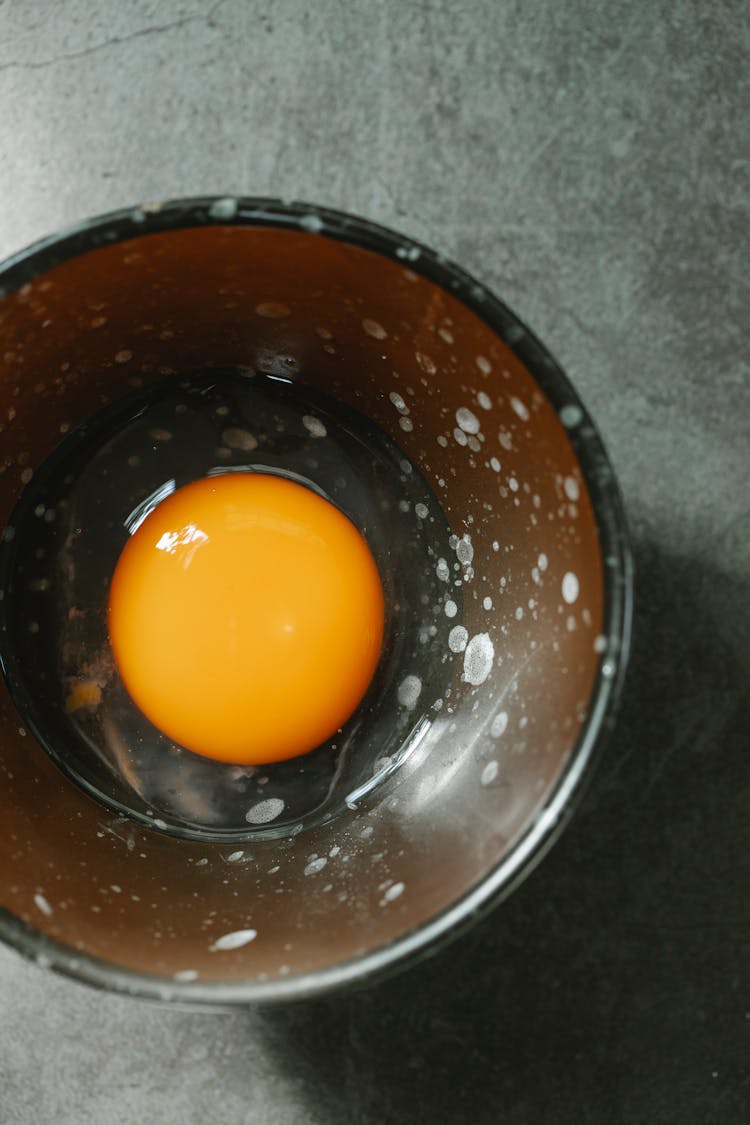 Fresh Egg Yolk In Bowl Arranged On Table