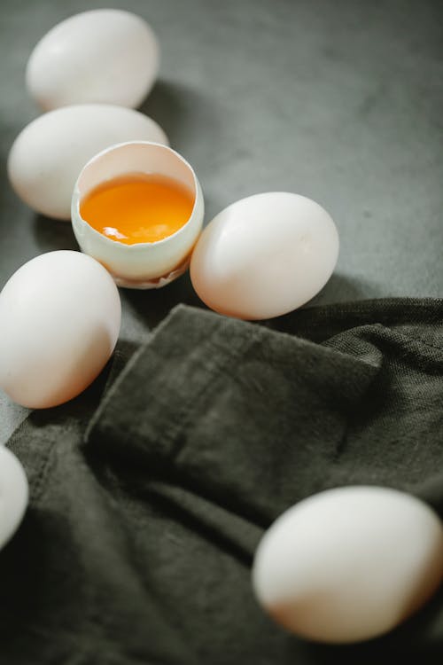 Free Whole and broken eggs placed on table near black towel Stock Photo