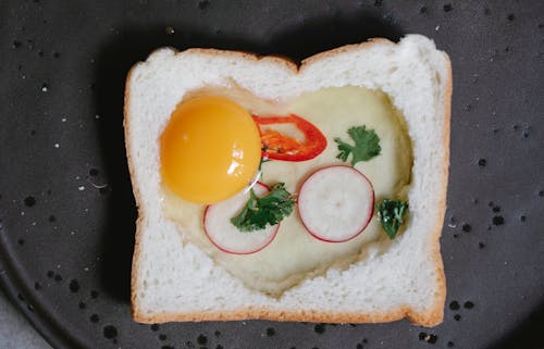 Top view yummy raw egg toast with white bread reddish and chili pepper placed on pan