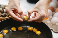 Crop woman breaking quail egg into pan