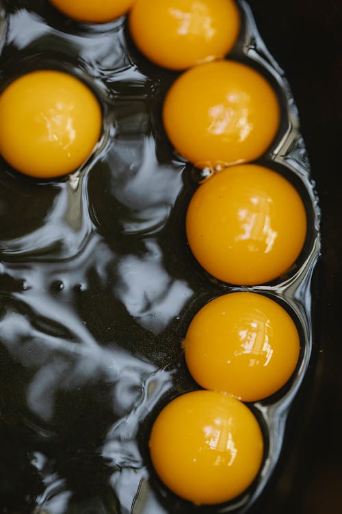 Free Top view abundance of quail eggs with yellow yolks cooking in black pan during breakfast preparation in kitchen at home Stock Photo
