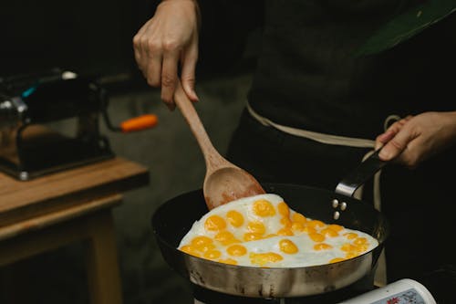 Free Crop faceless chef frying quail eggs in pan Stock Photo