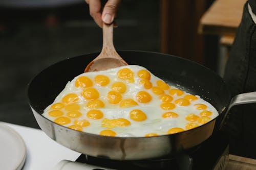 Crop unrecognizable chef frying tasty quail eggs on pan