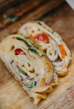 High angle yummy scrumptious egg roll with tomatoes and red onion cut in slices on wooden board