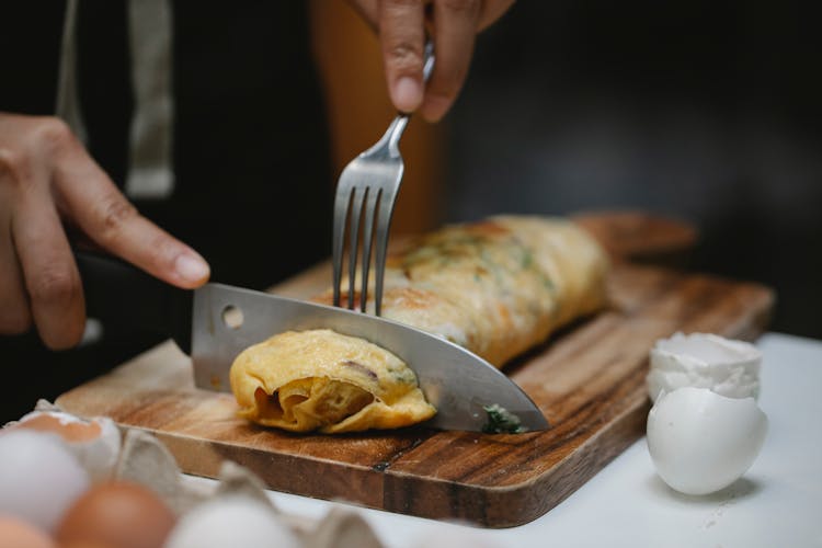 Crop Unrecognizable Chef Cutting Egg Roll In Kitchen