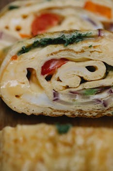 Close-up of a scrumptious vegetable omelette roll with fresh ingredients.