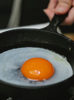 A close-up view of a fried egg cooking in a cast iron pan. Perfect breakfast scene.