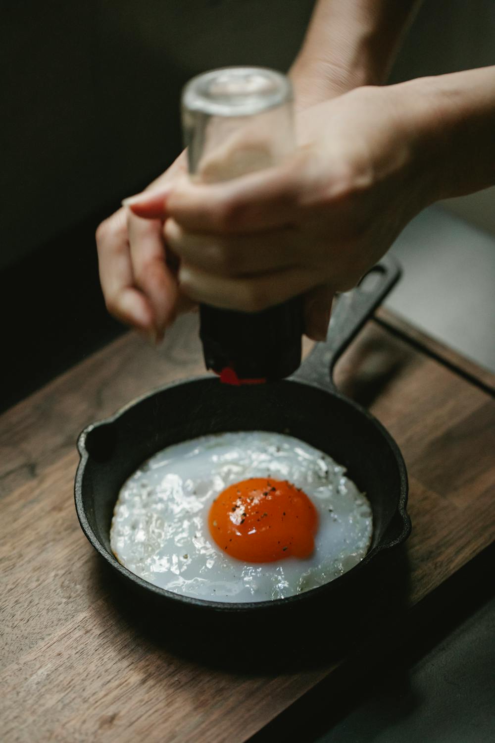 Woman adding condiment to fried egg · Free Stock Photo
