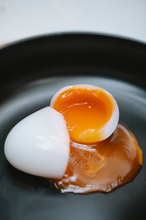 High angle of tasty homemade soft egg with yolk leaked on plate for meal