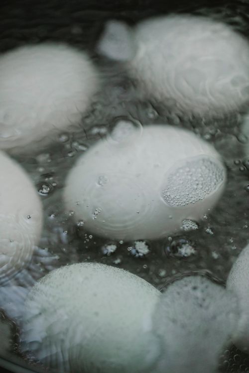 Free High angle of eggs boiling in hot water with foam in pan in kitchen Stock Photo