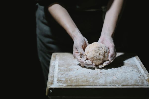 Hands stretching and folding sourdough dough on a floured surface, from the Complete Sourdough Bread Baking Levels 1 to 4 course