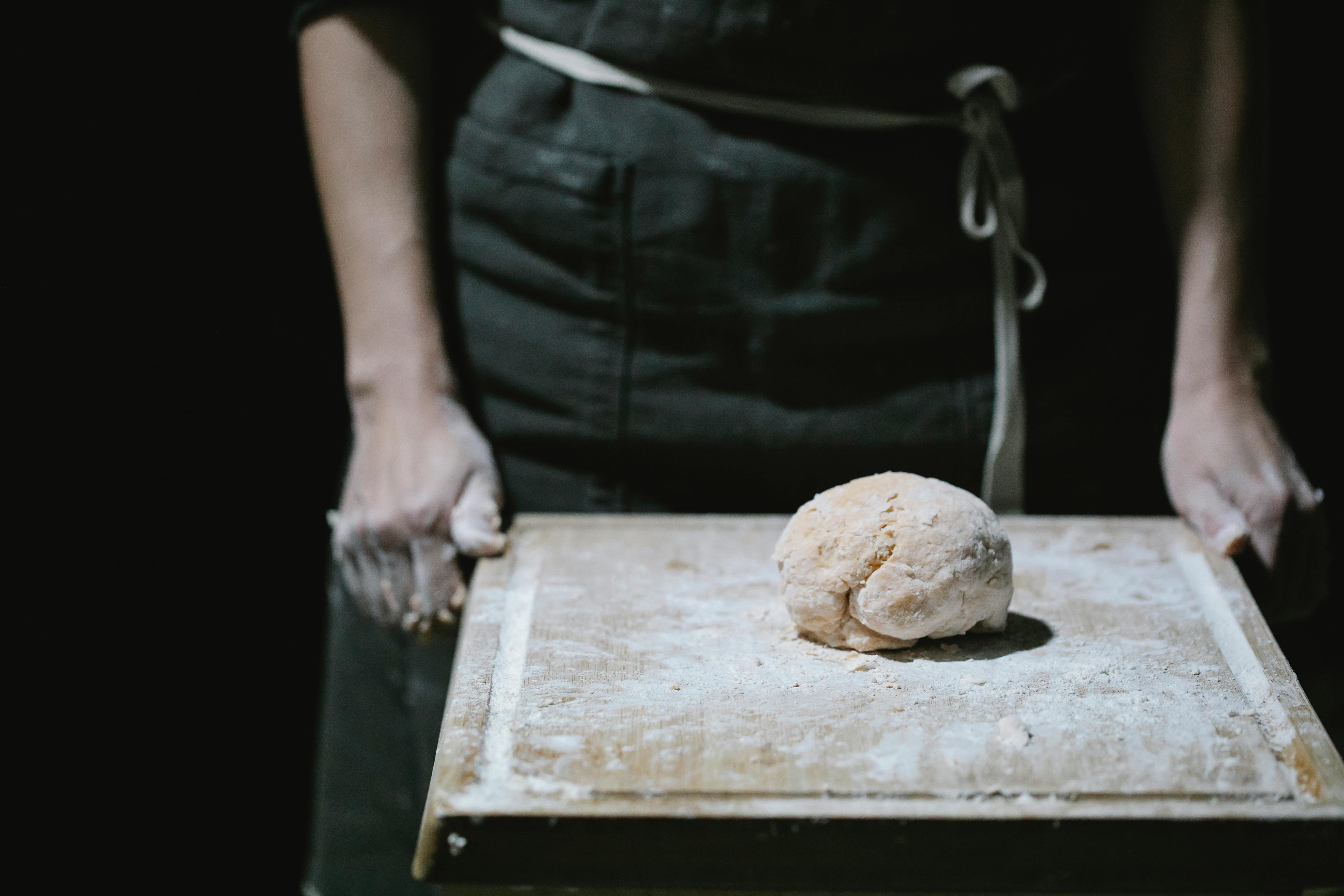 baker in apron standing at table with dough