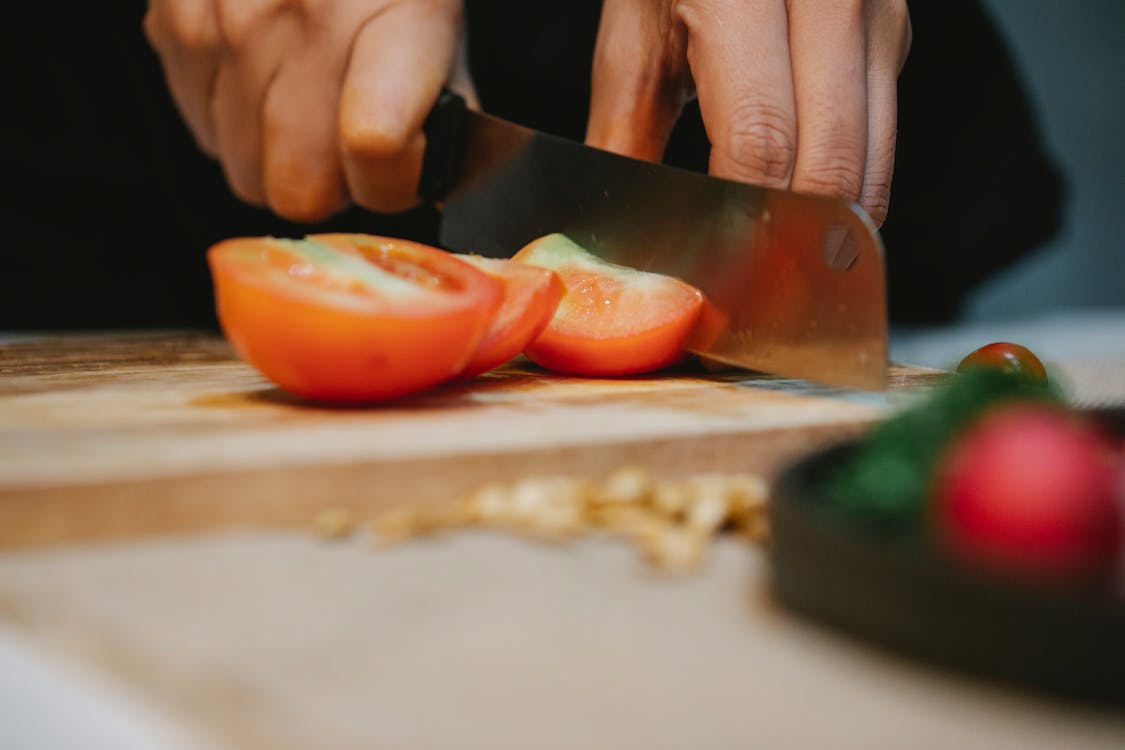 Chef slicing tomato on chopping board in kitchen