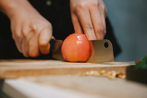Free Cook cutting tomato on chopping board for recipe Stock Photo