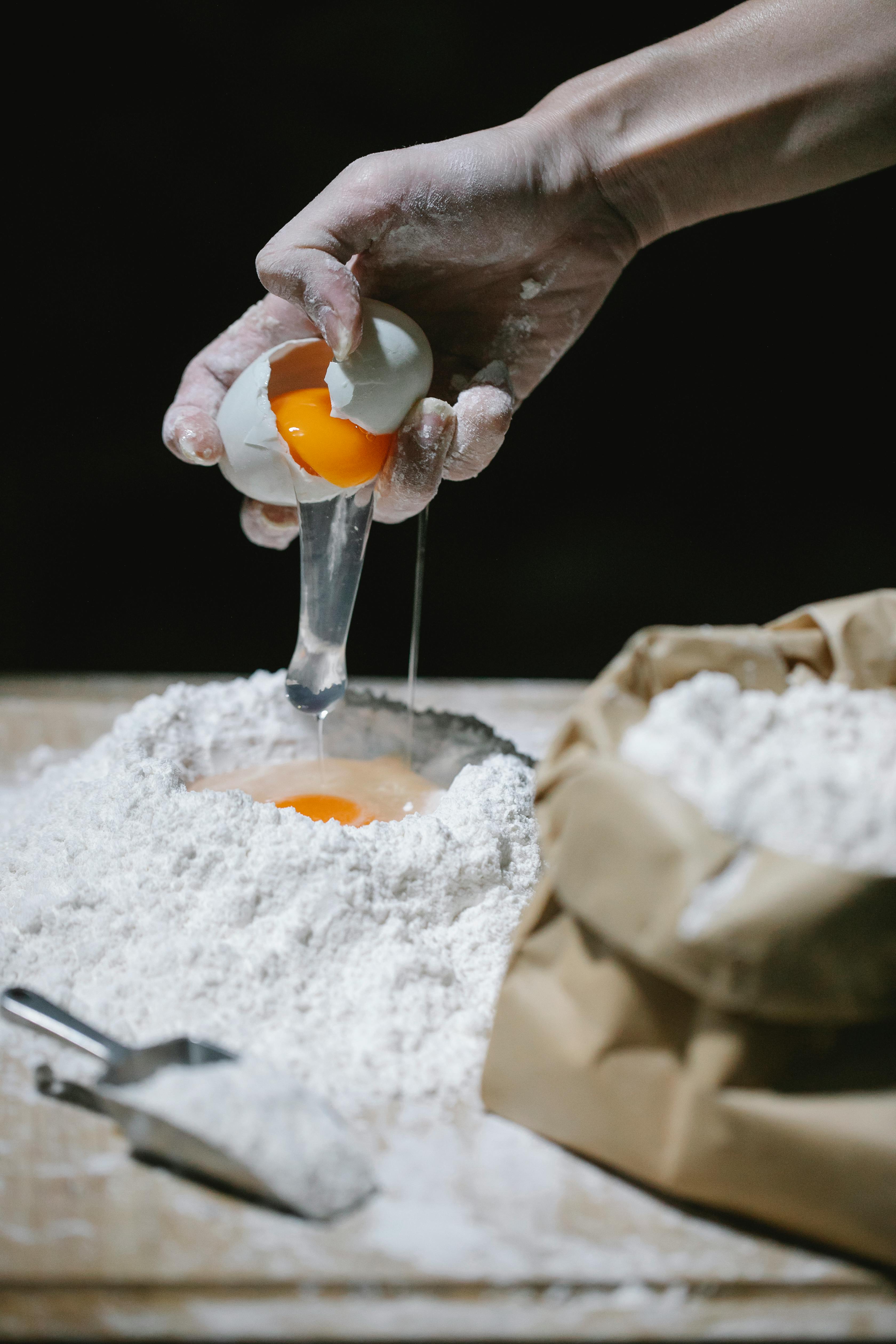 chef breaking egg into flour for pastry