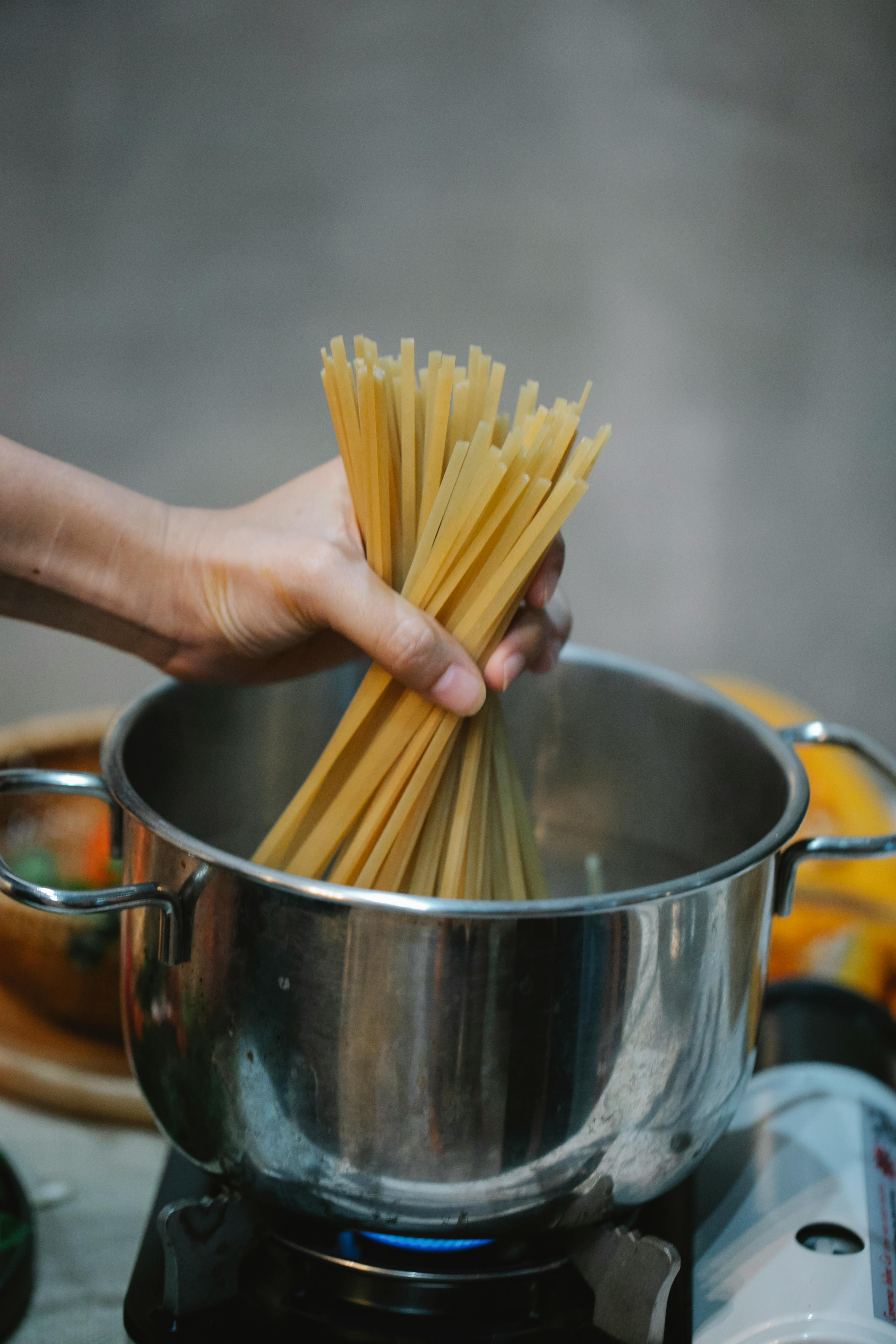 woman putting raw spaghetti in hot water