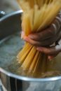 High angle of crop anonymous female putting pasta in saucepan with boiling water while preparing meal