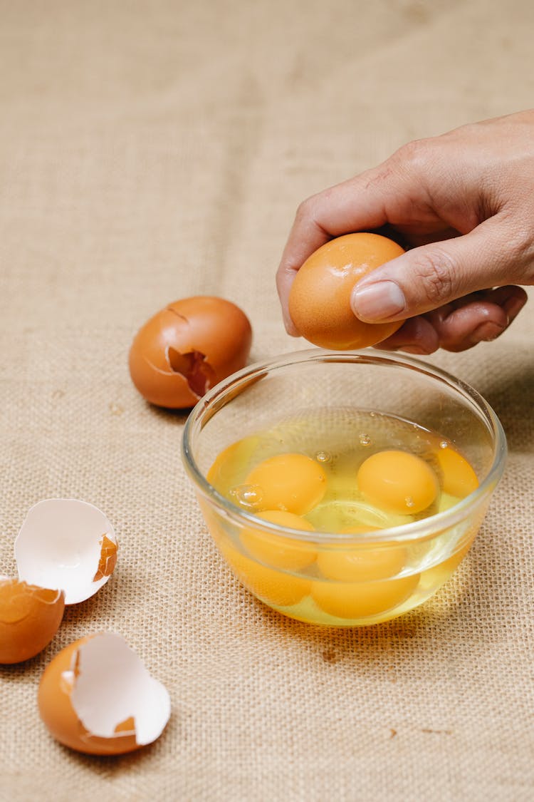 Person Breaking Eggs In Bowl