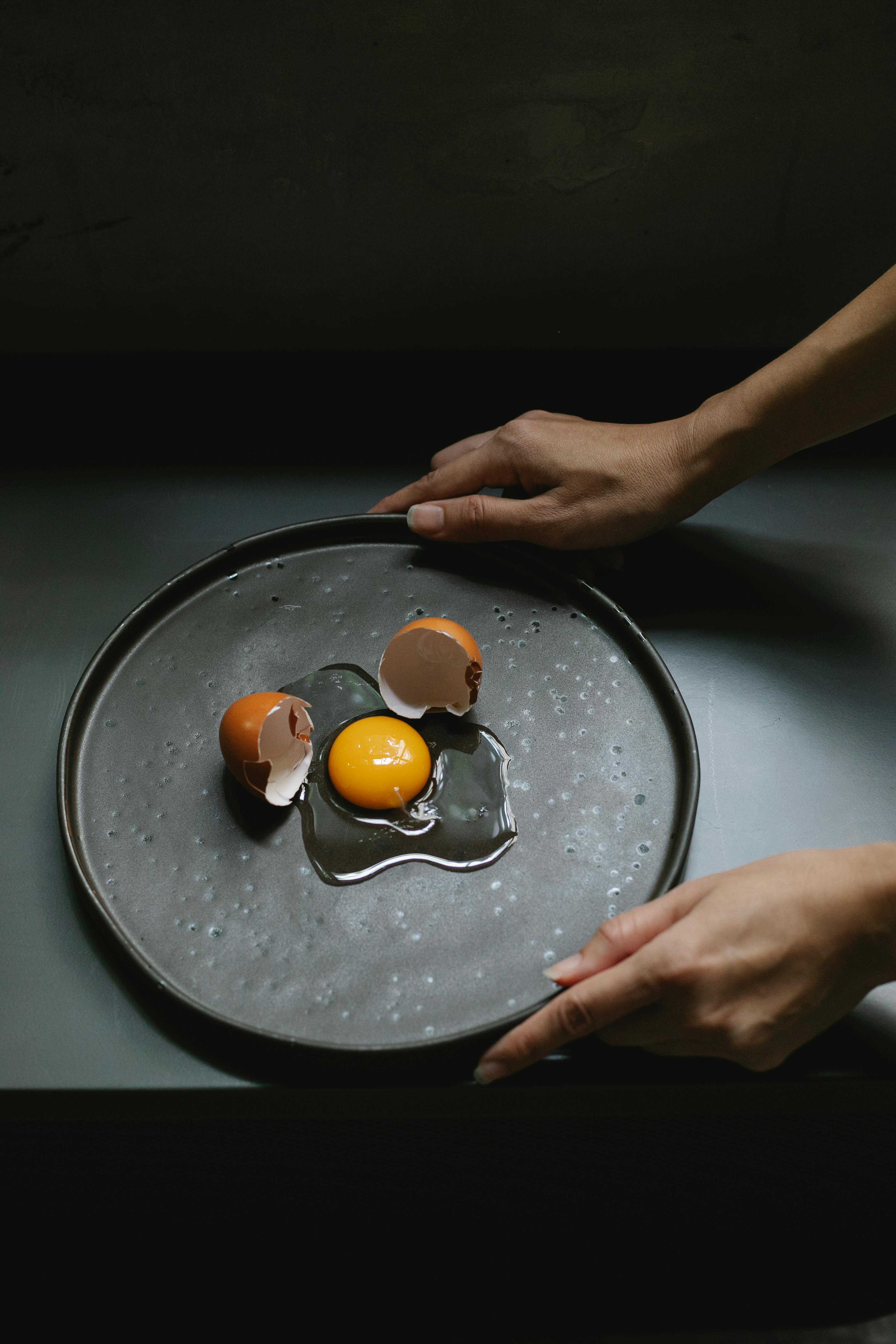 person holding plate with broken egg