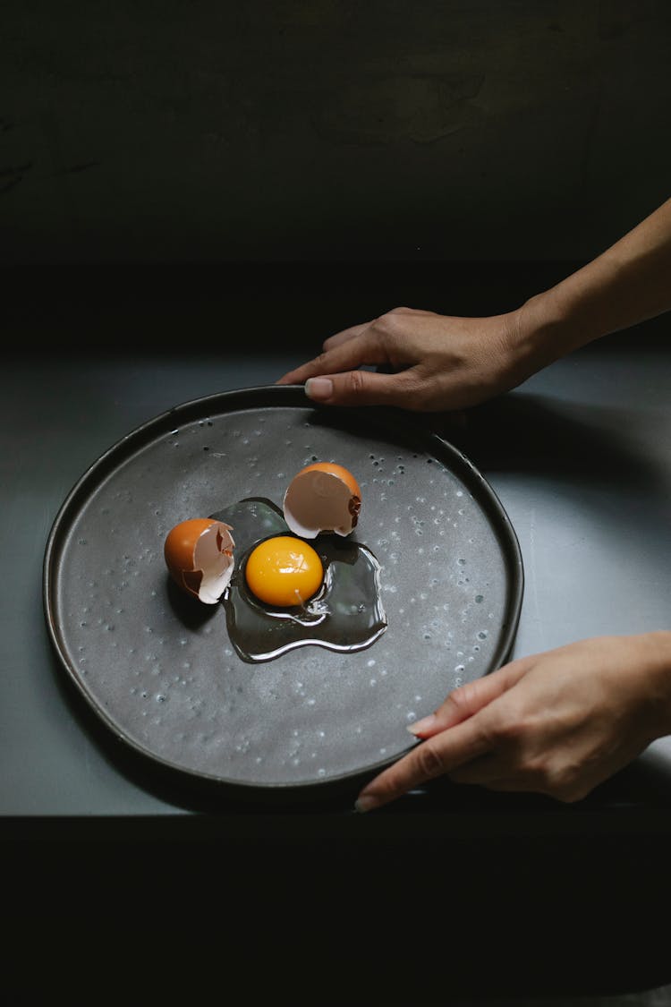 Person Holding Plate With Broken Egg