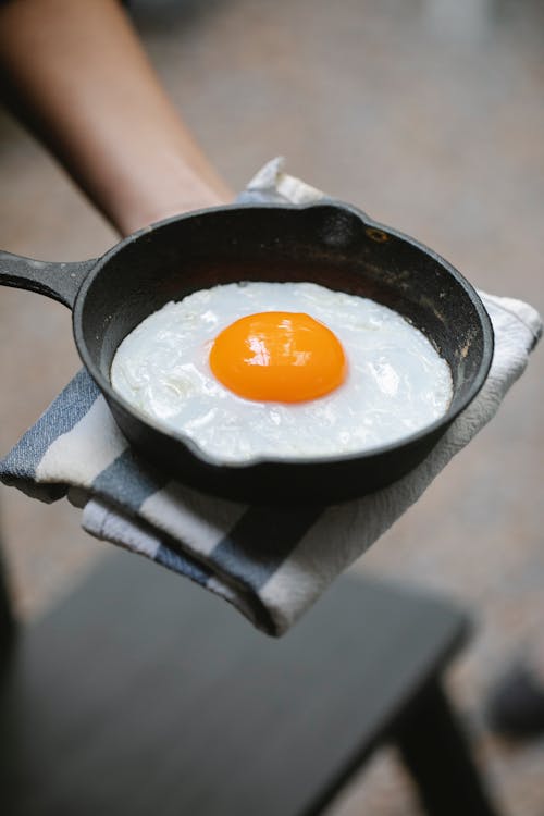 Person holding pan with fried egg