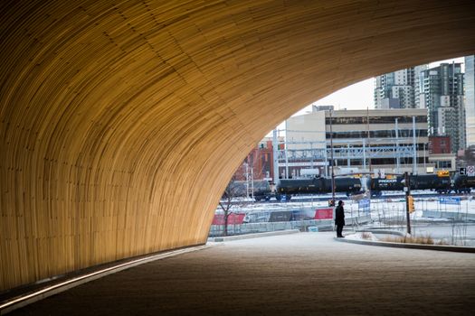 A person stands in a modern tunnel with a cityscape backdrop in Calgary, Alberta.