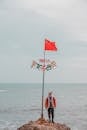 A Man in Red Jacket Standing on the Rock