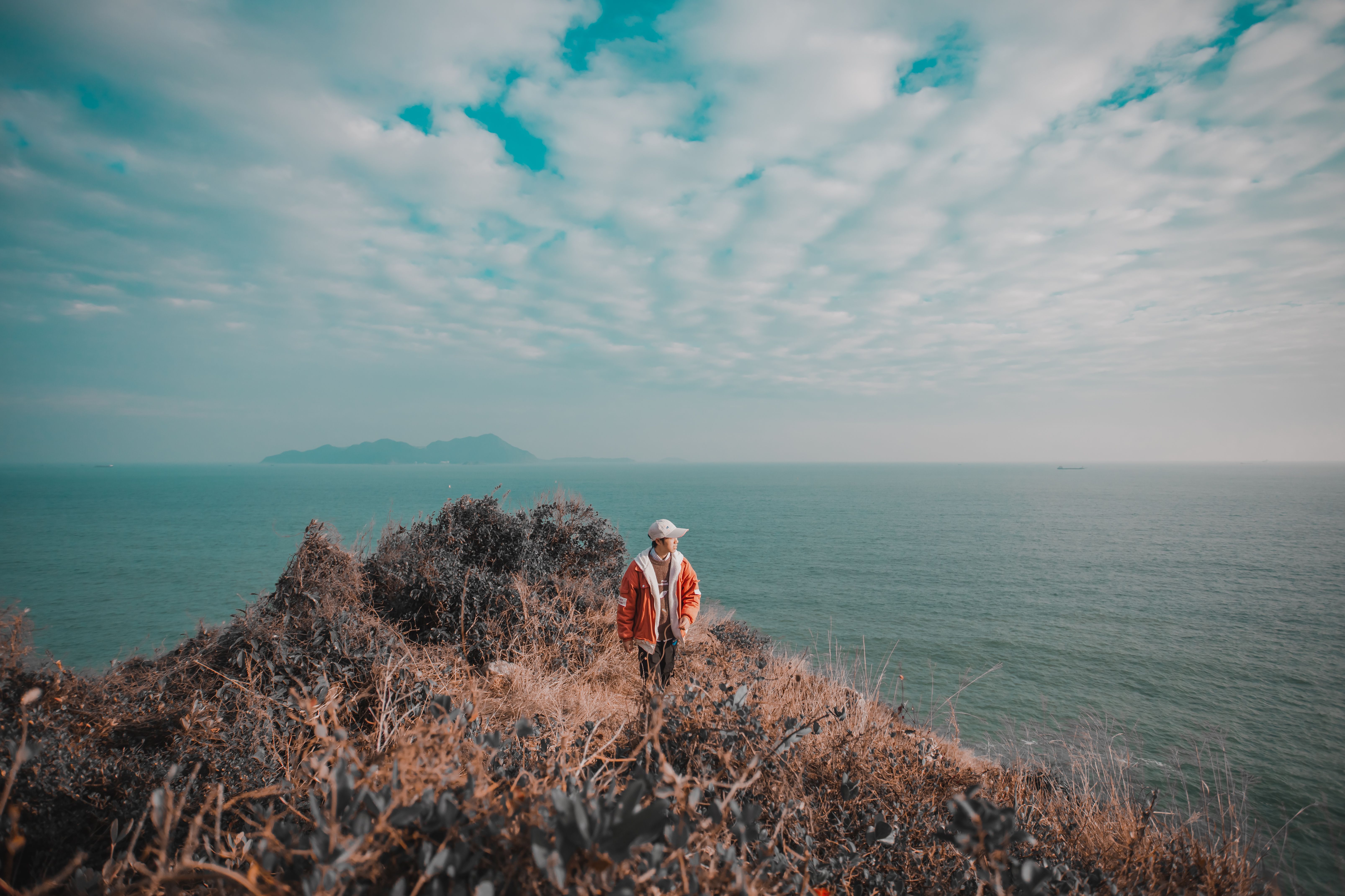 A Man in Orange Jacket Standing on the Mountain · Free Stock Photo