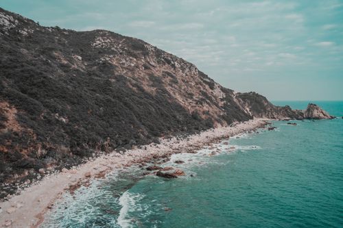 Free A breathtaking aerial view of a rocky coastline with turquoise waves crashing along the shore. Stock Photo