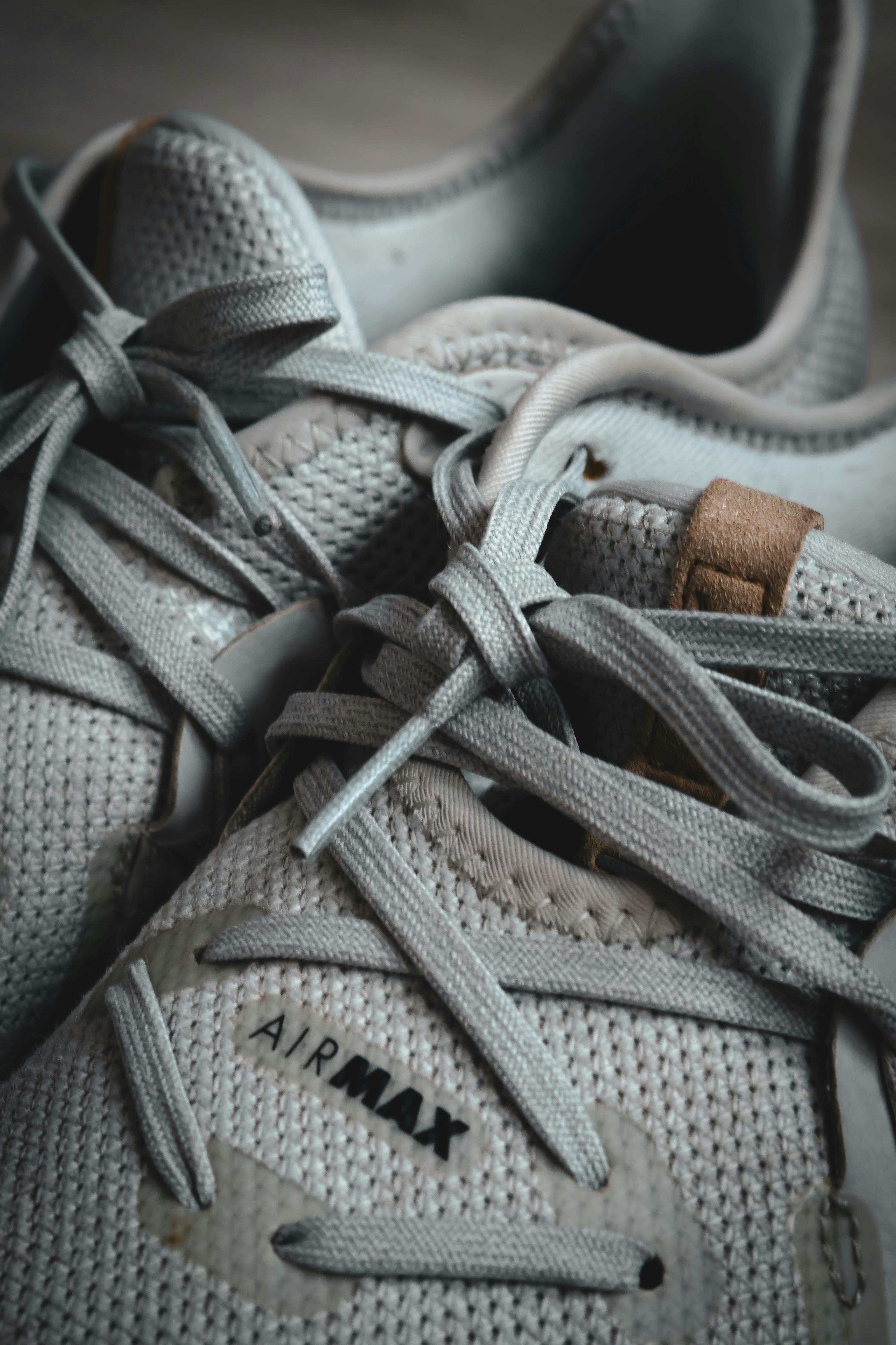 Detailed shot of gray sneakers featuring prominent shoelaces and branding.