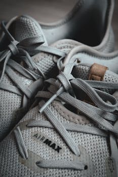 Detailed shot of gray sneakers featuring prominent shoelaces and branding.