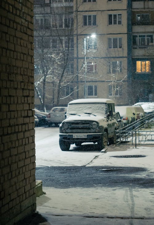 Vehicles parked on snowy road near residential building