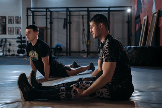 Two men performing MMA stretching exercises on a gym mat indoors.