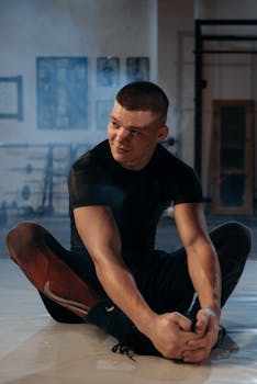 Focused athlete stretching indoors at gym, preparing for workout.